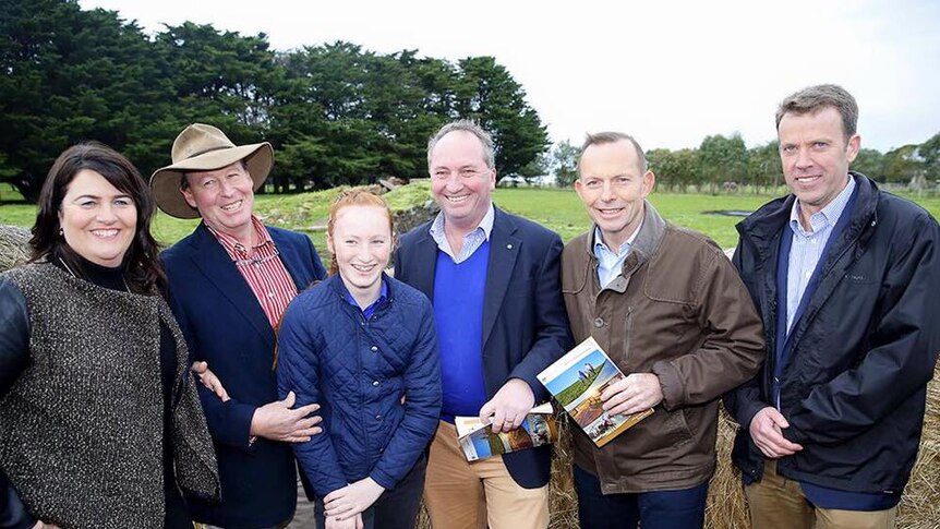 Politicians and farmers standing on a dairy farm