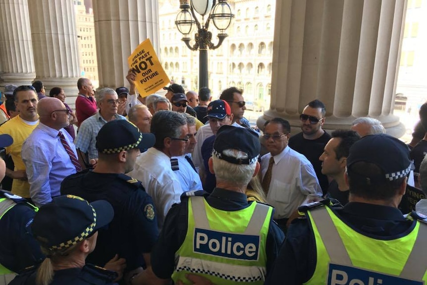 Police form a line to stop taxi protesters entering Victoria's Parliament.