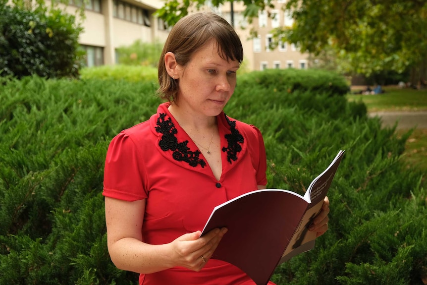 Dr Bianca Fileborn reading a report  at Melbourne University.