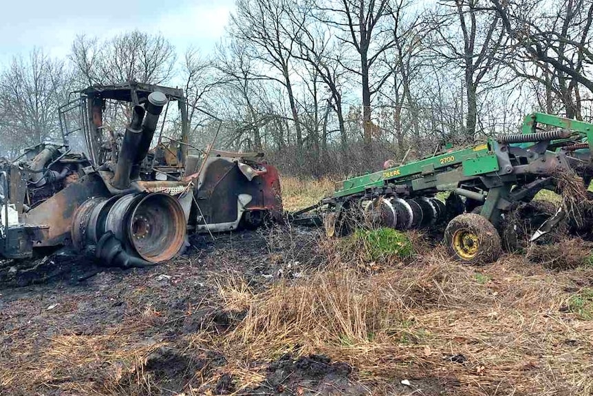 A burnt tractor in a paddock.