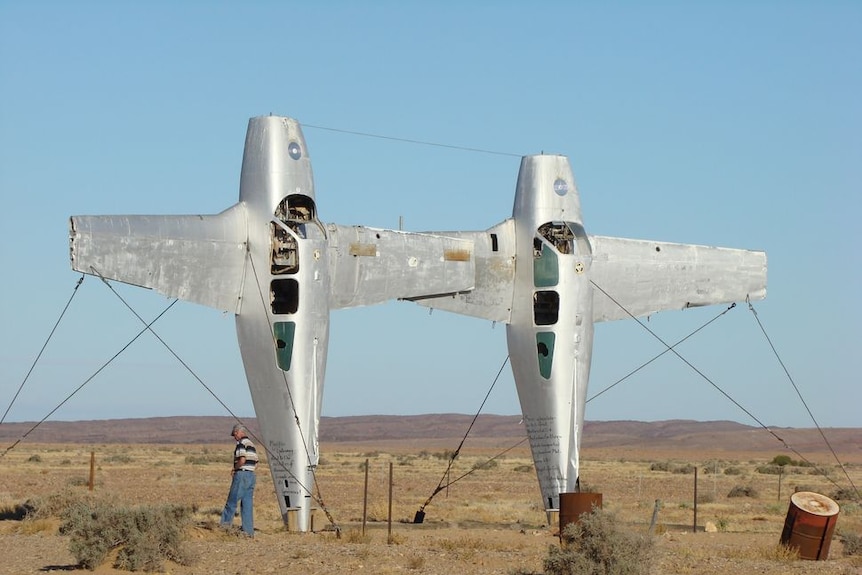 Two aeroplanes stood on their tails side-by-side in the desert
