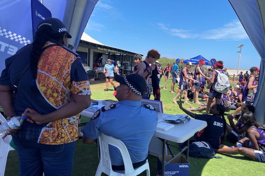 group of people chilling on the lawn, photo from inside a police tent 