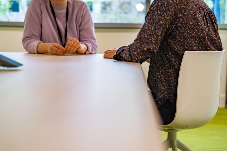 Two people, who faces not shown, negotiating at an office table