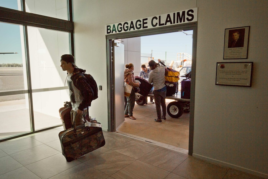 Passengers collect their luggage from a trailer outside the arrivals hall at Charleville airport.