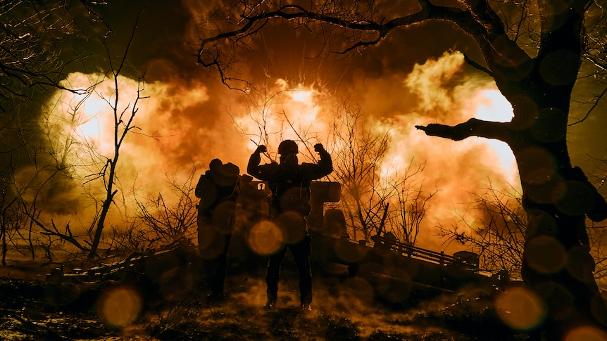 A silhouette of soldiers in front of a fire. 