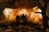 A silhouette of soldiers in front of a fire. 