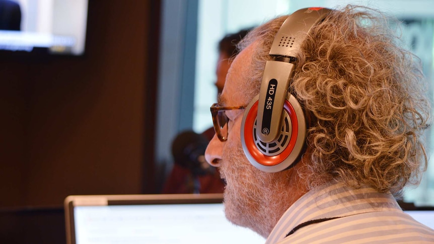 Jon Faine, wearing headphones, looks up during an interview.