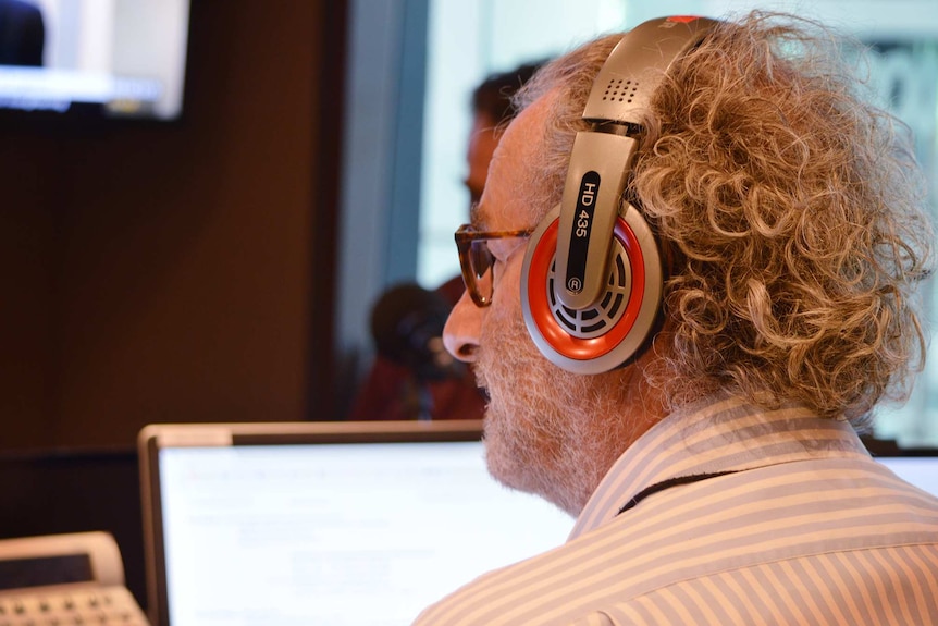 Jon Faine, wearing headphones, looks up during an interview.