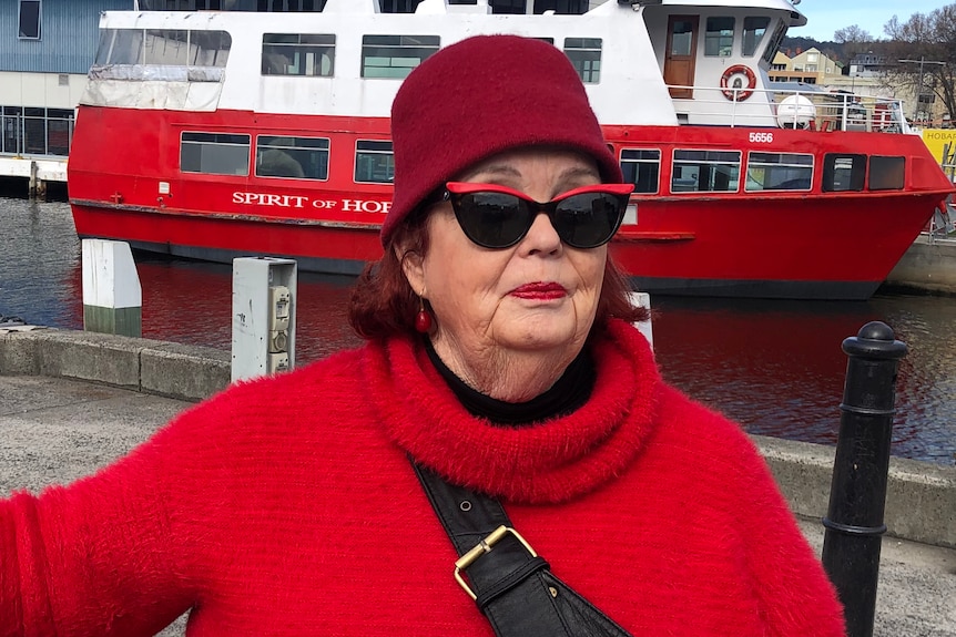 A woman poses in front of a boat at Hobart's waterfront.