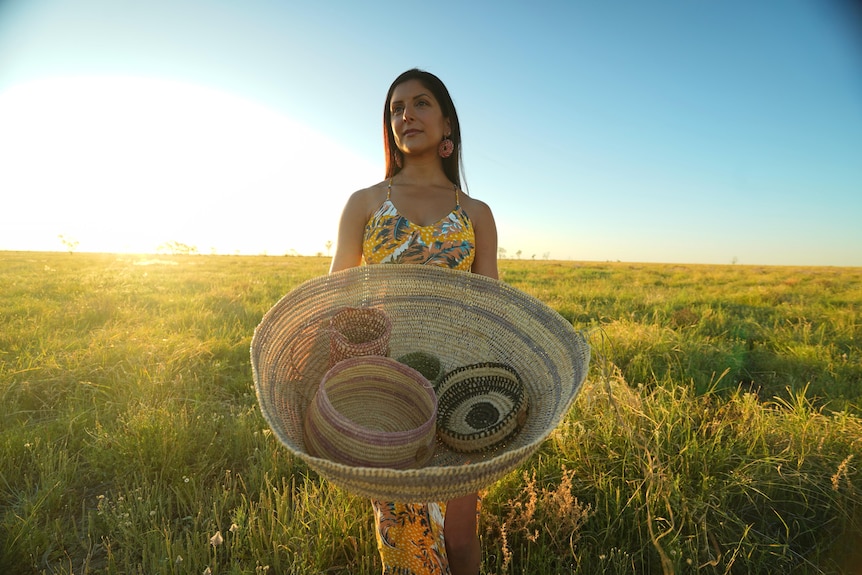 Woman standing in field holding baskets