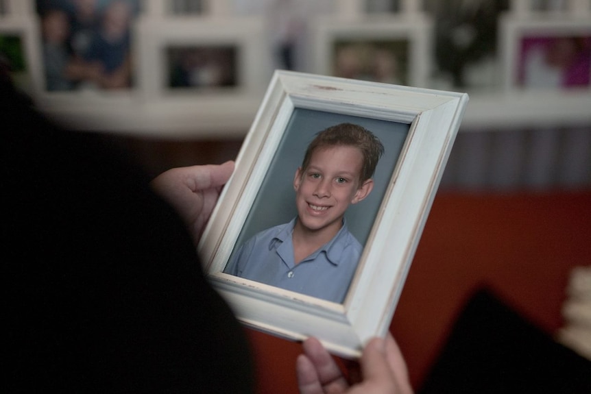 A mother holds a school portrait of her young son.