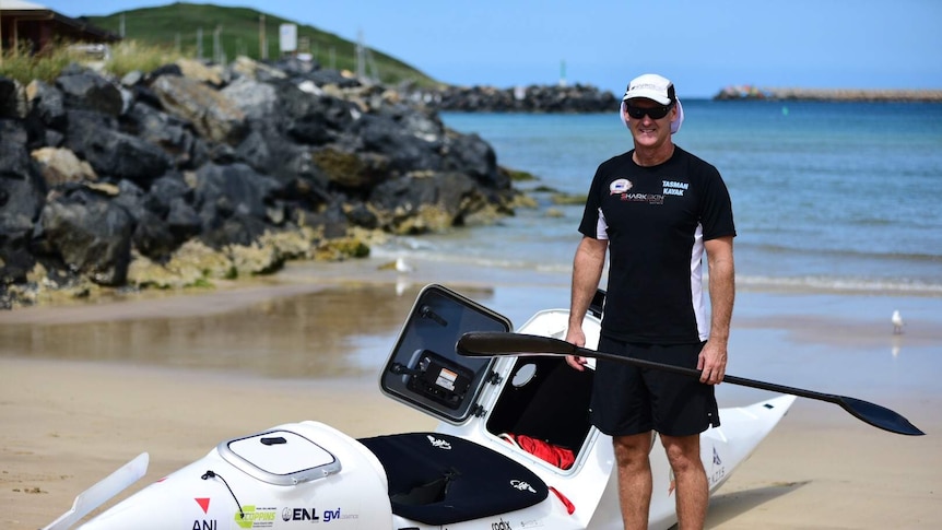 Man  standing on a Coffs beach with paddle oar in hand