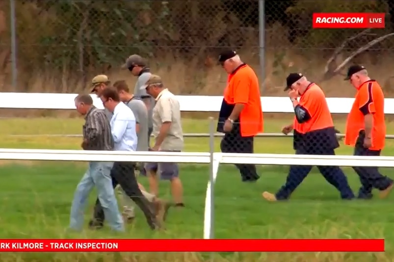 Patrons and officials walk the rack track at Kilmore looking for metal spikes after some were found on the turf.