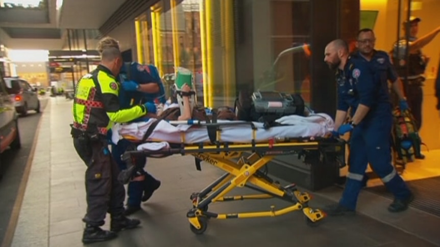 Paramedics wheel a patient on a trolley