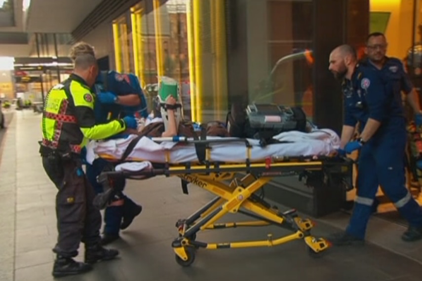 Paramedics wheel a patient on a trolley