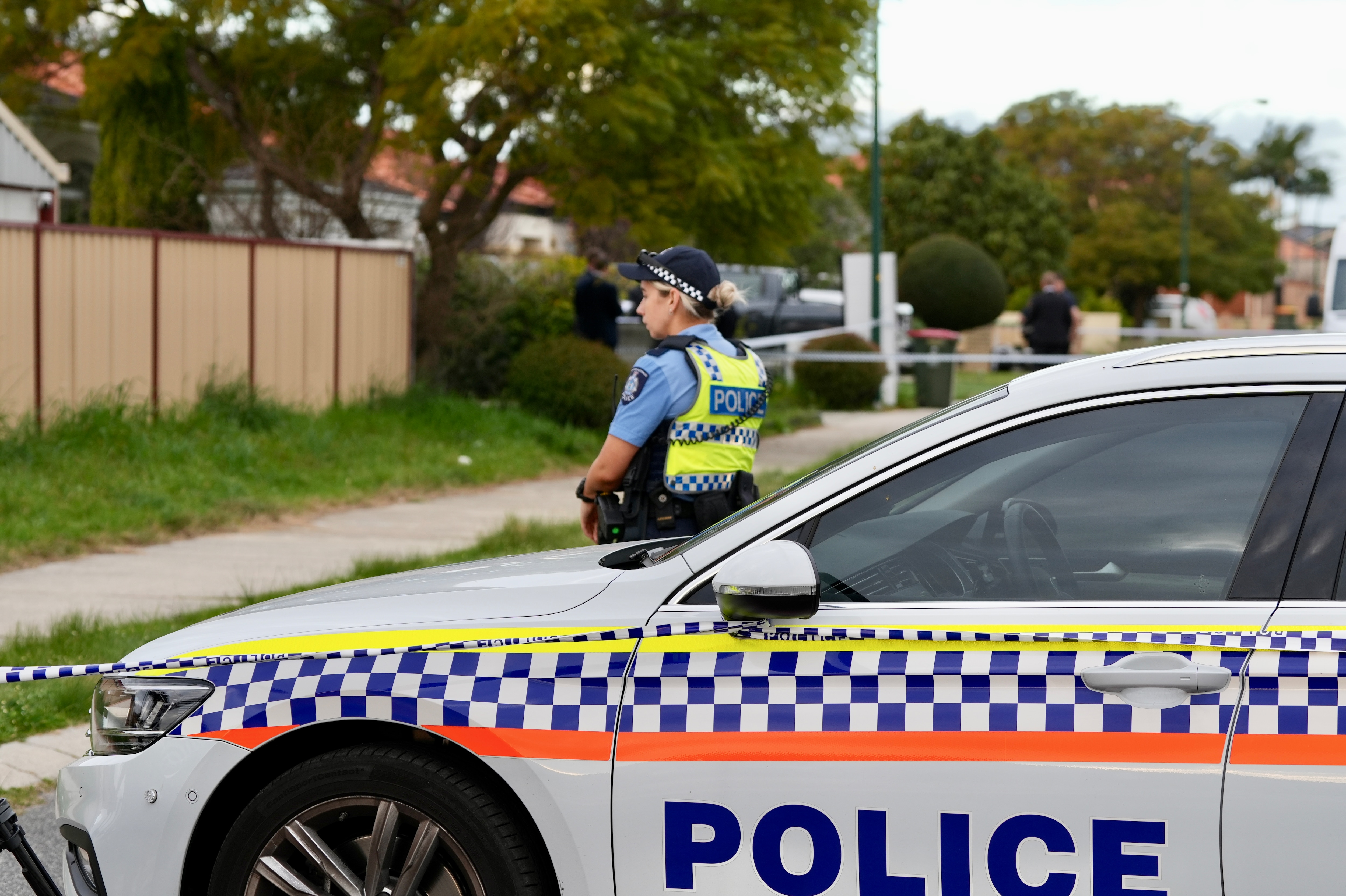 A police car with a police woman leaning against it. 