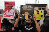 Activists hold up posters with slogans in Indonesian during a rally.