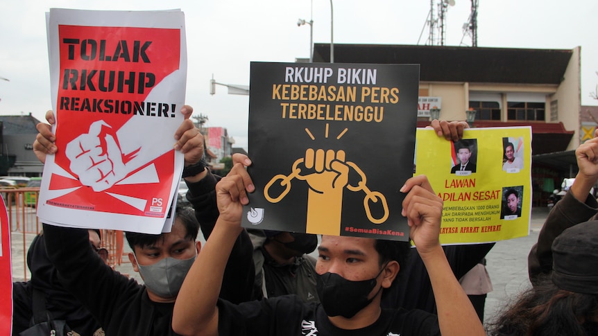 Activists hold up posters with slogans in Indonesian during a rally.