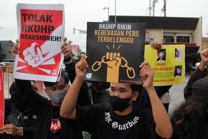 Activists hold up posters with slogans in Indonesian during a rally.