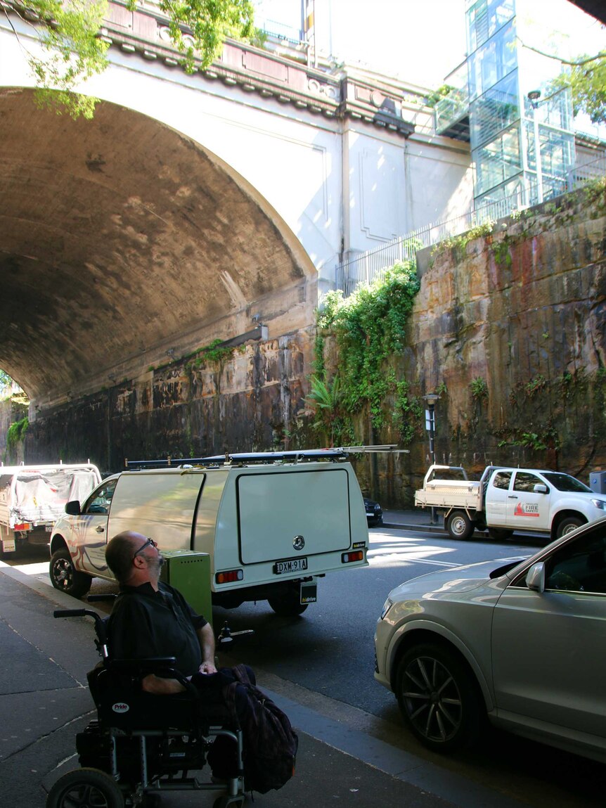 Andrew Emmerson in a wheelchair, looking up at the lifts for the Sydney Harbour Bridge