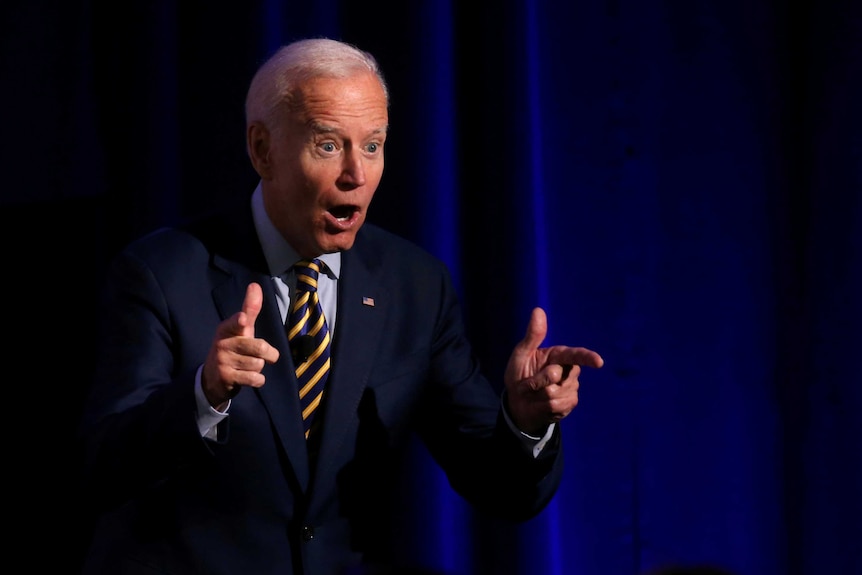 A man in a suit making finger guns