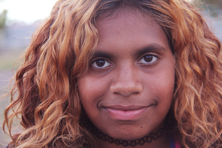 A young Aboriginal woman looks directly at the camera