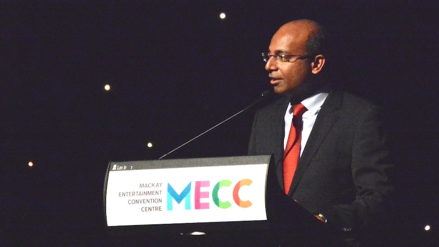 A man making a speech at a lectern on a stage