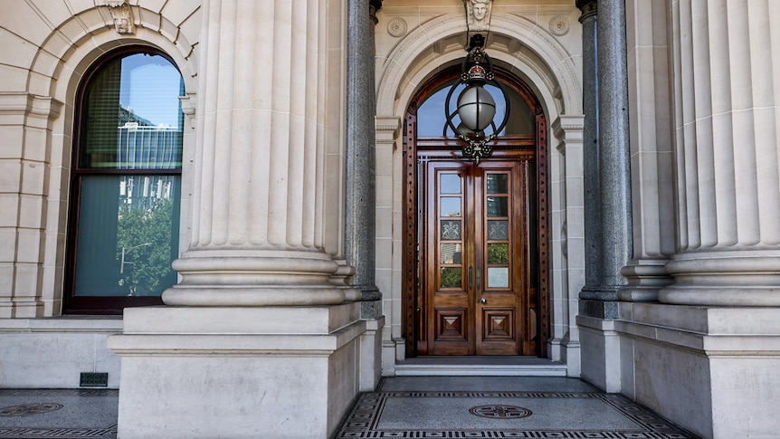 A close-up of a large, ornate wooden door at the front of Victoria's Parliament house