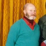 A fuzzy, low res photo of a bearded 50ish man balding wearing green wool jumper