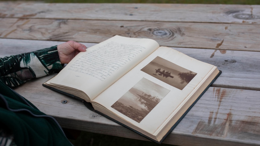 A woman's hand holding a book open.