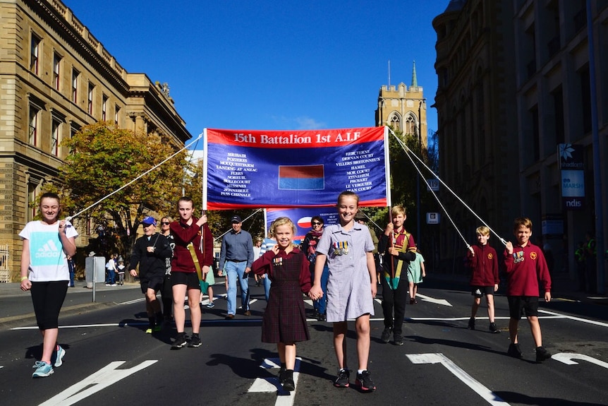 Children carry flags in Hobart's Anzac Day parade.