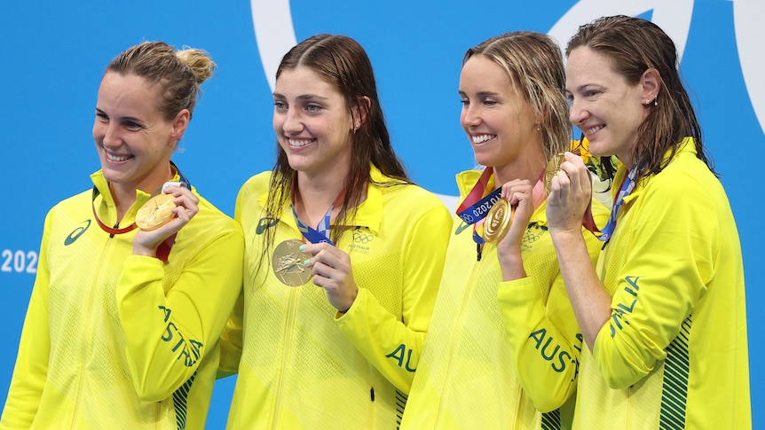 Four women in yellow tracksuits hold their Olympic Games gold medals