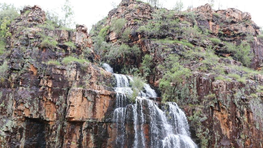 a waterfall running off an escarpment into a river