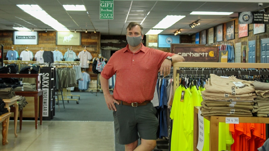 A man in a red shirt and a covid mask stands in a retail store