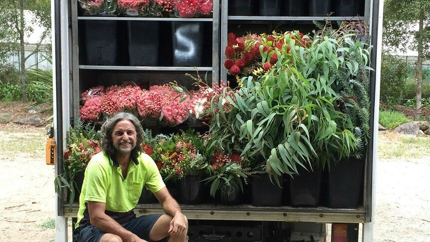 Craig sits in front of his truck which is full of a range of native flowers