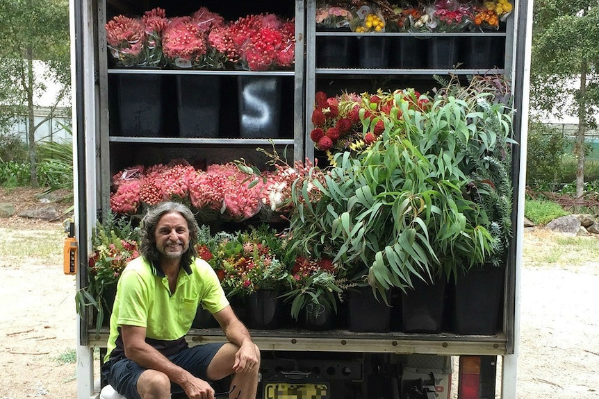 Craig sits in front of his truck which is full of a range of native flowers