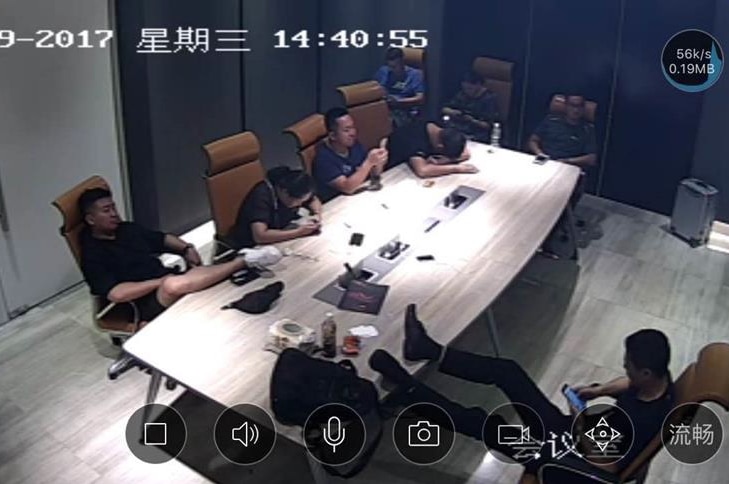 Security camera still image shows people lounging around in the conference room of USGFX's Shanghai office.