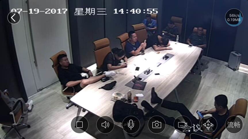 Security camera still image shows people lounging around in the conference room of USGFX's Shanghai office.