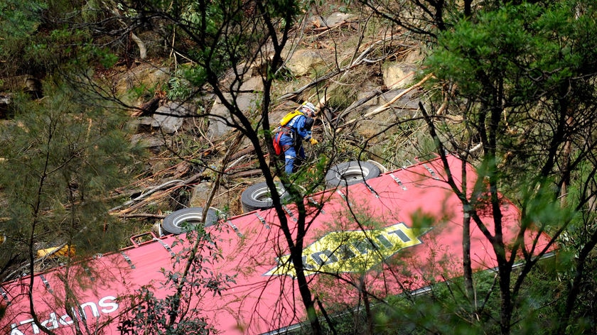 A rescue worker climbs down to a truck that crashed through a freeway safety barrier north of Sydney today.