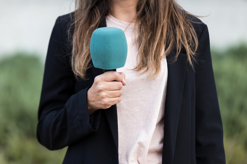 Image générique d'une femme journaliste tenant un microphone.