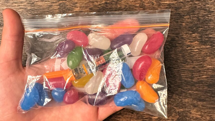 A clear zip lock bag with jellybeans and a vile of insulin inside. 