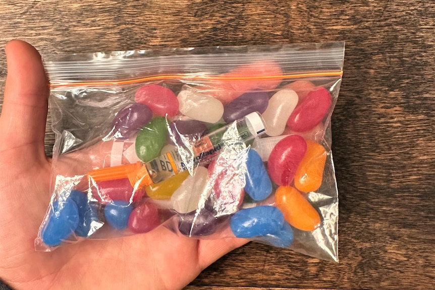 A clear zip lock bag with jellybeans and a vile of insulin inside. 