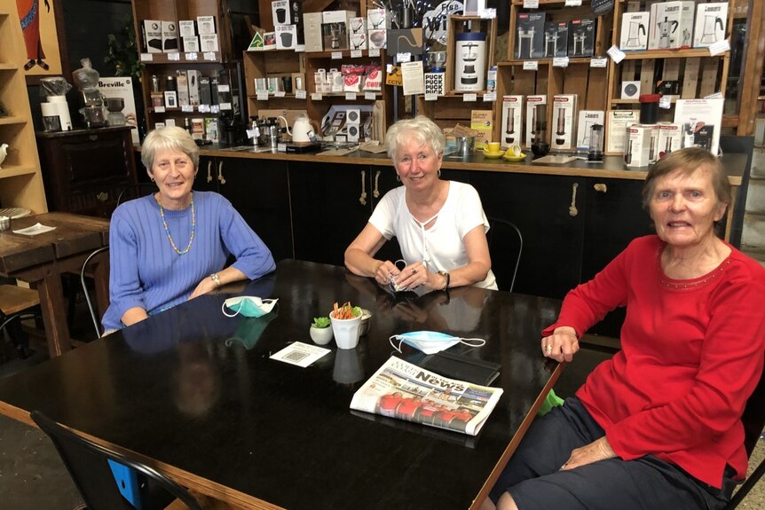 Three women sitting in a cafe smiling 