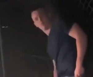 A man in a black t-shirt looks at the camera in a very low resolution image.