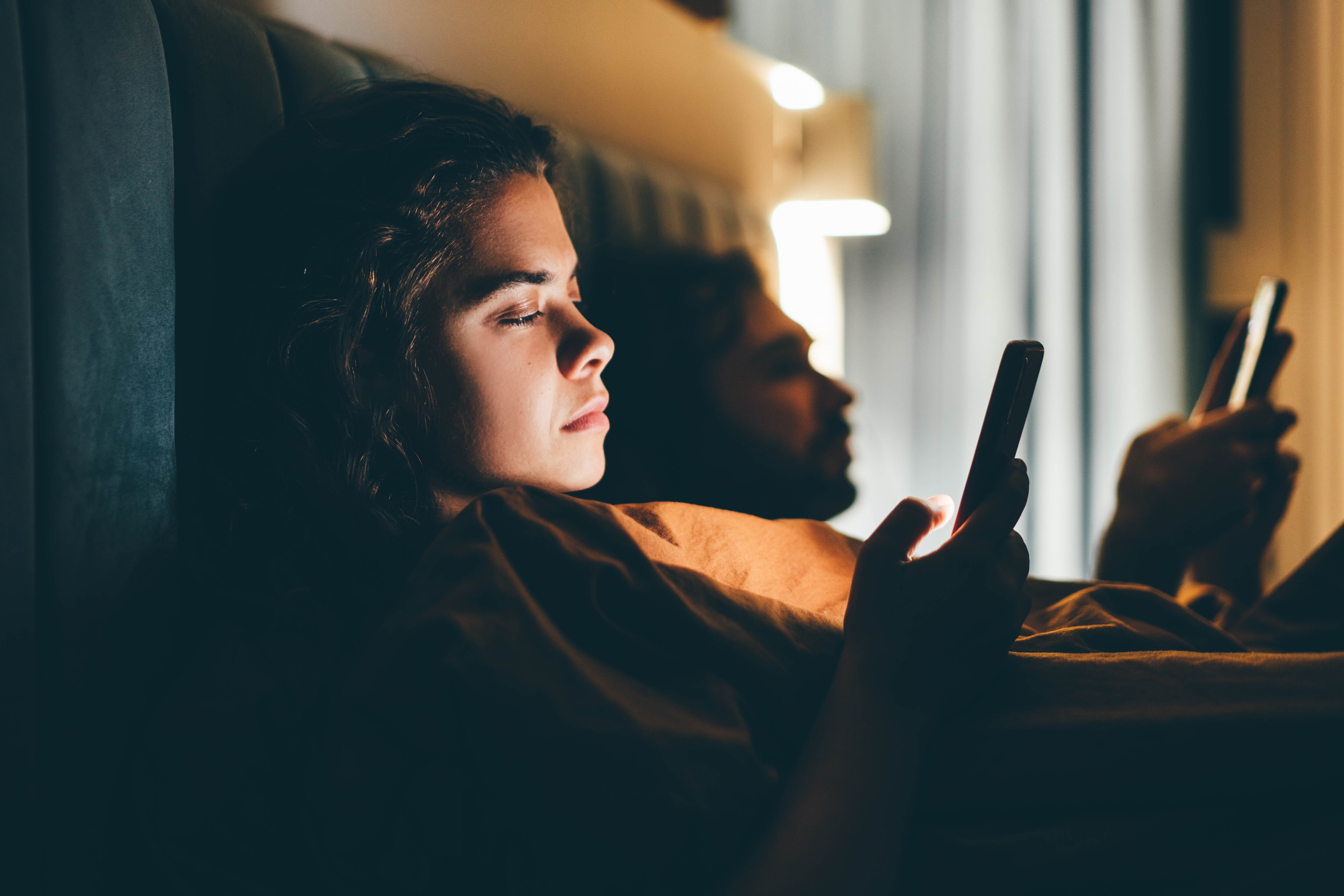A couple looking at the phones in the dark in bed