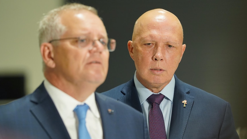 Morrison looks out of frame, slightly blurry, as Dutton stands beside him.