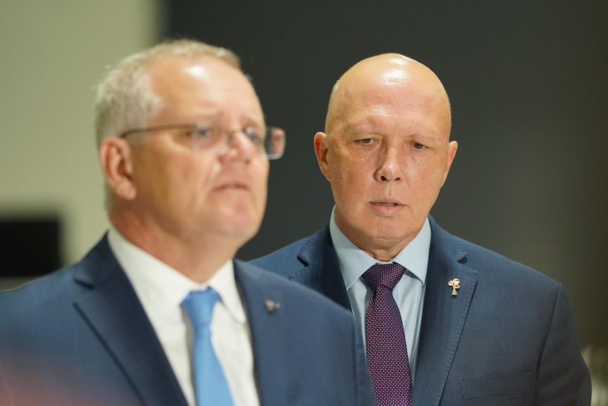 Morrison looks out of frame, slightly blurry, as Dutton stands beside him.