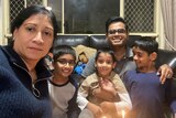 Jayani Dalath, her husband and three children sit on a couch in a house.