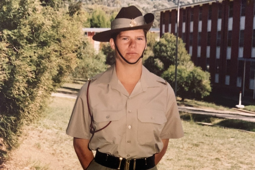 A woman standing in army uniform with her hands behind her back