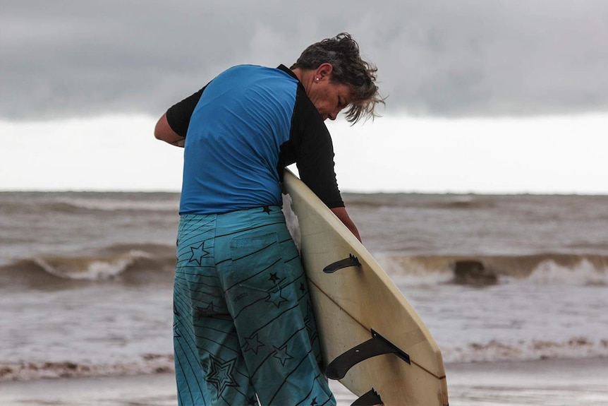surfer with her board during storm clouds